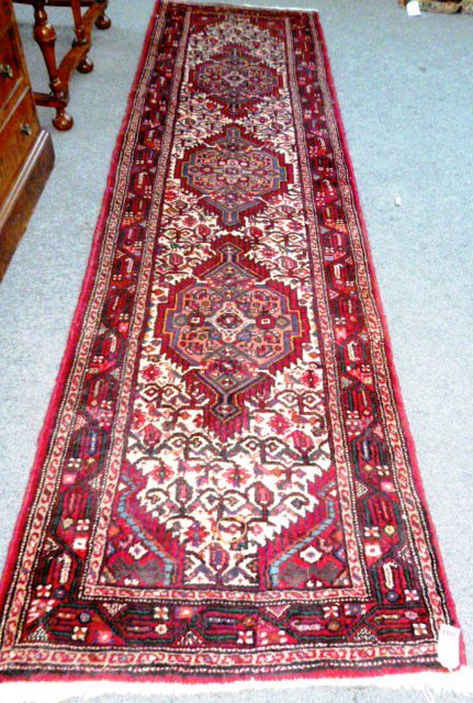 A Zagheh runner, Persian, the ivory herate field with three bold diamonds, a madder boteh and vine