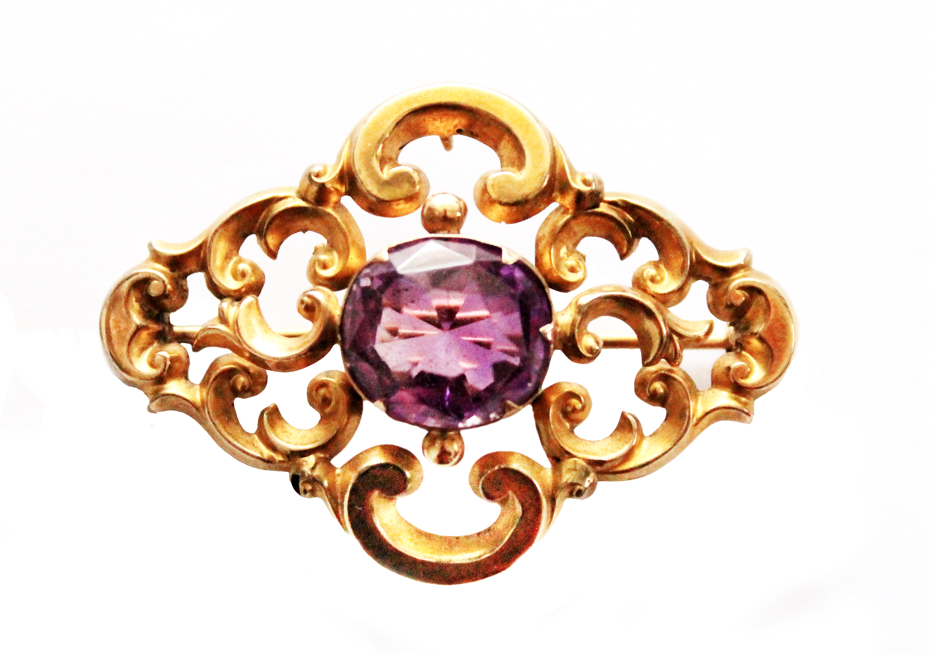 A Victorian gold and amethyst set single stone brooch, in a pierced openwork scrolling design,