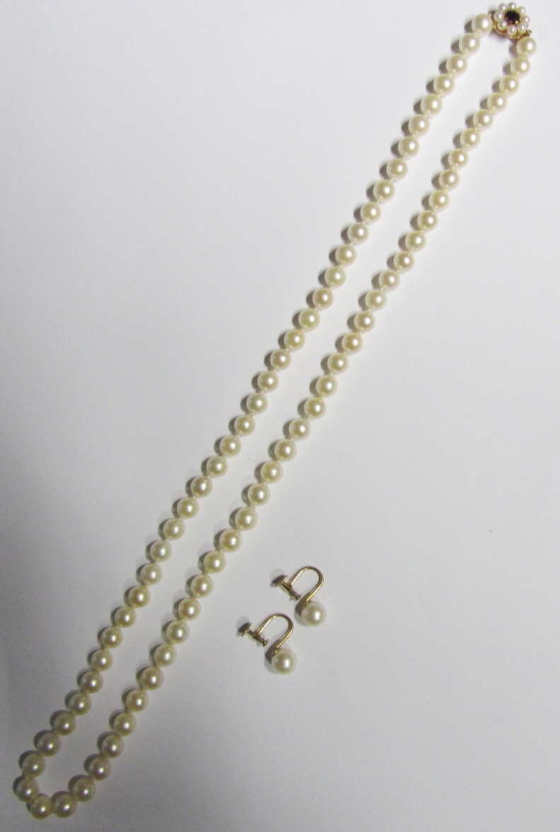 A single row necklace of uniform cultured pearls, on a gold, cultured pearl and gem set cluster