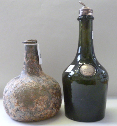 An 18th century green glass wine bottle, 16.5cm high, and a 19th century silver mounted green