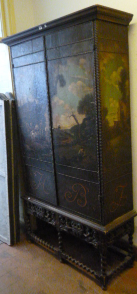 A 17th century style two door cupboard with studded leather veneer depicting landscapes on a