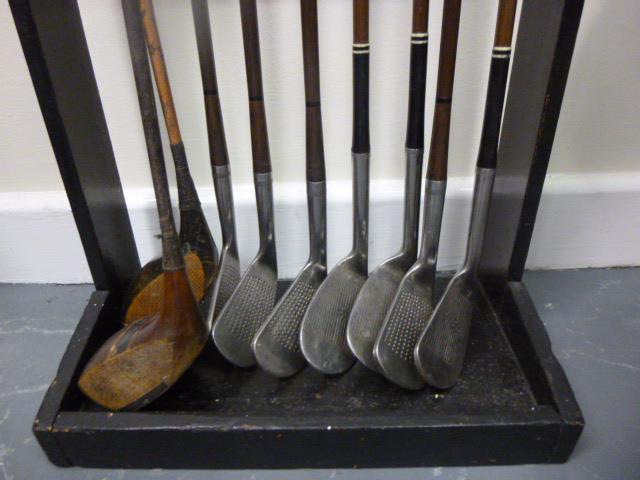 Golf - A wooden display stand holding 9 assorted clubs - Irons, 4 x Henry Cotton, 3 x Bobby