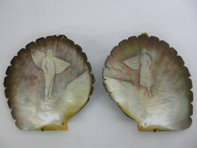 Two carved oyster shells depicting a fisherman and woman, with hanging hooks, approximately 115cms
