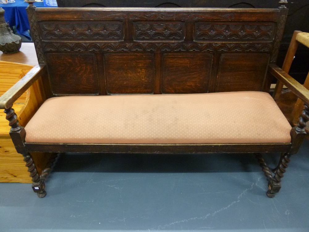 Carved oak settle with a four panel back and barley twist supports, 151x56x109cms, with padded