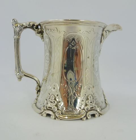 JOHN KEITH A VICTORIAN SILVER MILK JUG having inverted body, all over tooled decoration, cast scroll