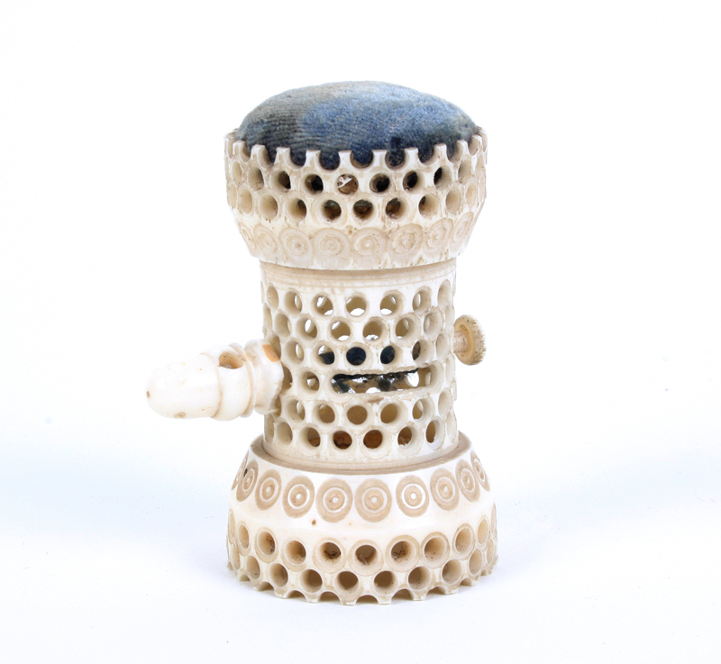 A pierced ivory combination tape measure and pincushion of standing cylinder form pierced with