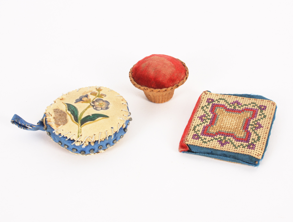 Two pincushions and a needlebook, comprising; a small basket woven pincushion, 3cm diameter, a