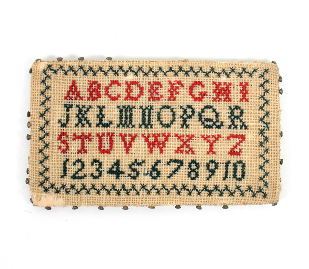 A sampler pin card, one side worked with upper case alphabet and numerals in red and green, the