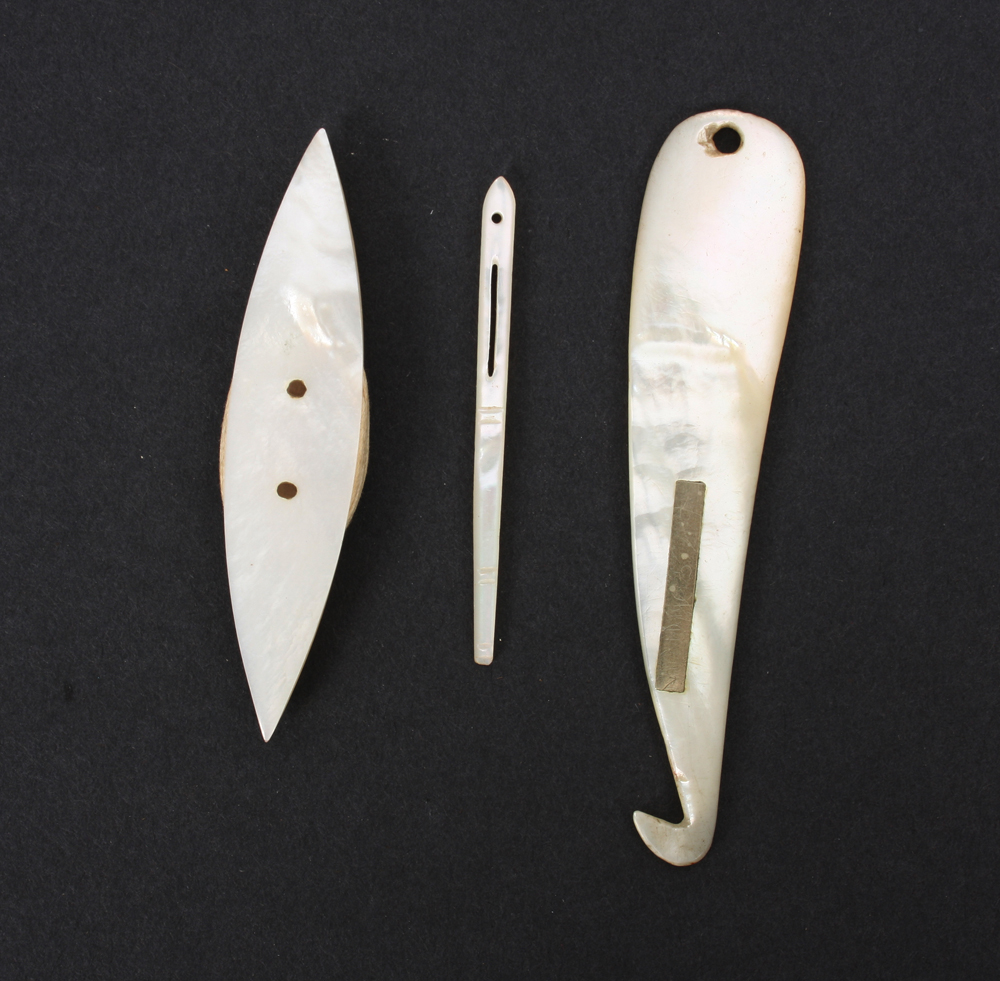 Three mother of pearl tools, comprising; an unusual curved purling hook, 8cm, a shuttle, and a