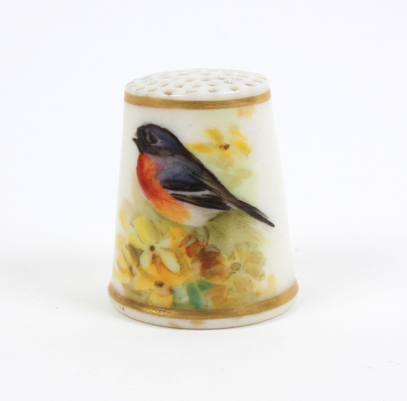 A Royal Worcester porcelain puce mark thimble, painted with a bird amid foliage, flowers to the