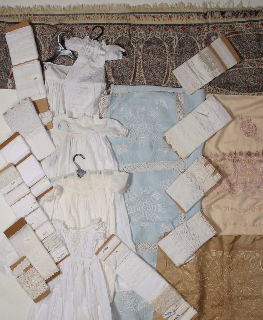 A group of baby wear, whitework trimmings and linen, including a paisley fold-over shawl, with