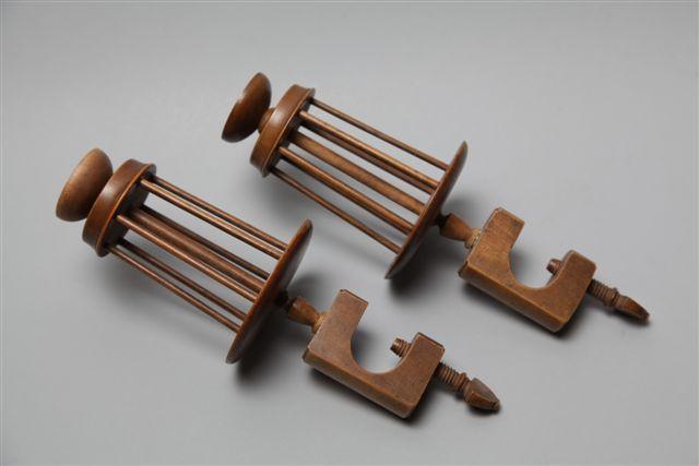 A pair of stained wood winding clamps, the book form frames below tapering reels surmounted by