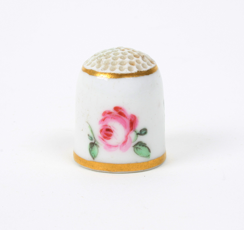 A 19th century porcelain thimble, probably French, painted with three flowers between gilt lines