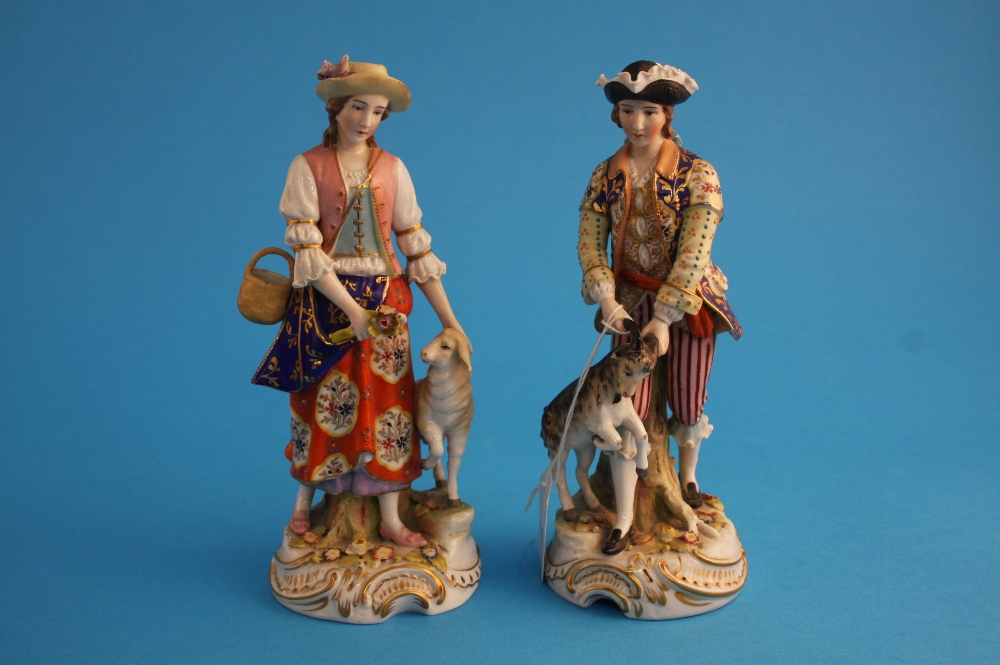 A pair of Continental porcelain figures of a gallant and a lady, a goat at his side and a lamb at