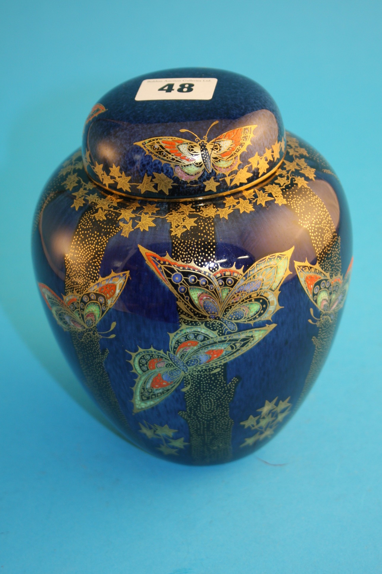 A Crown Devon lustre ginger jar of ovoid form, decorated with brightly coloured and gilt butterflies