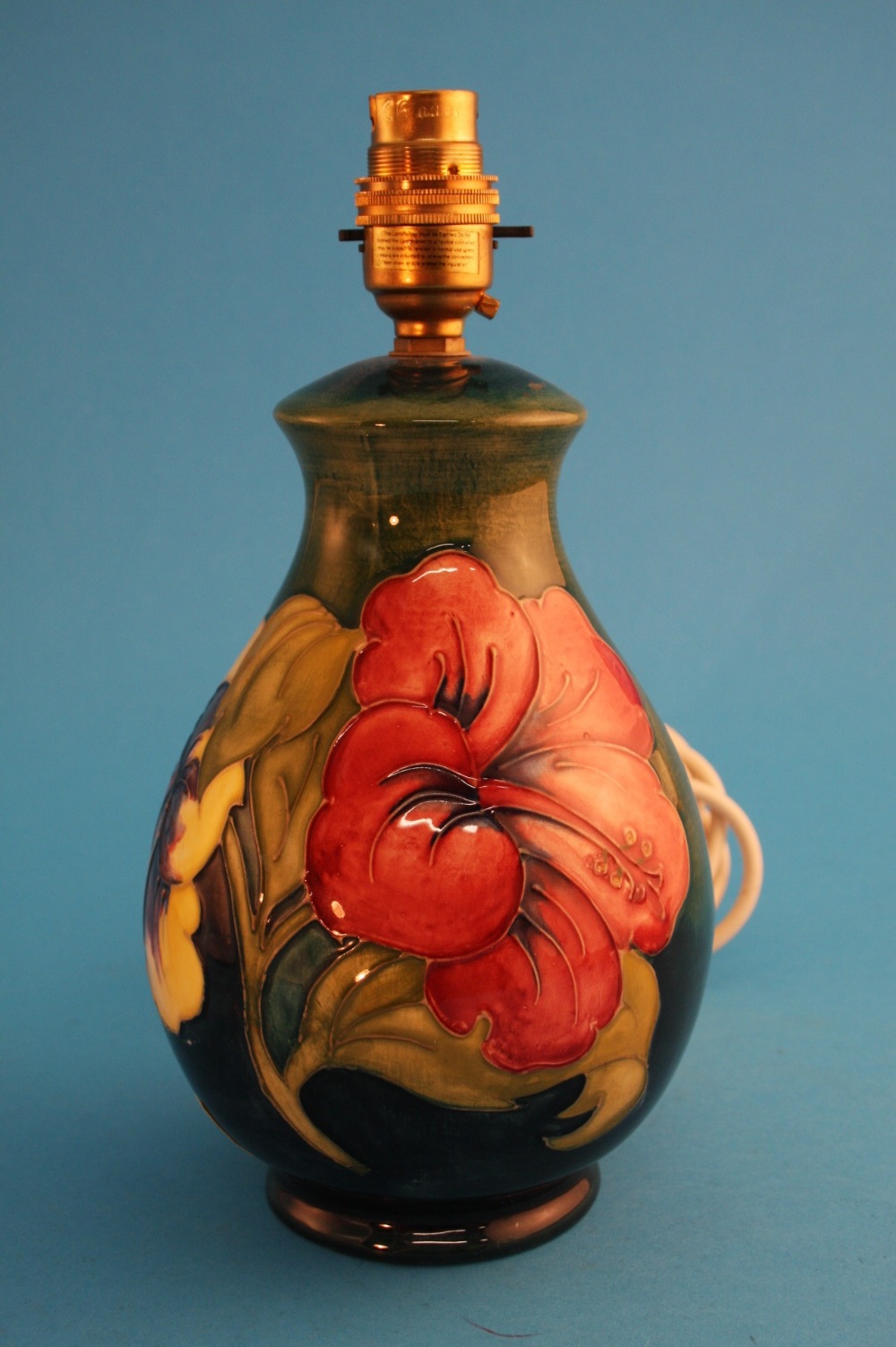 A small modern Moorcroft baluster shaped "Hibiscus" pattern table lamp on a graduating green ground,