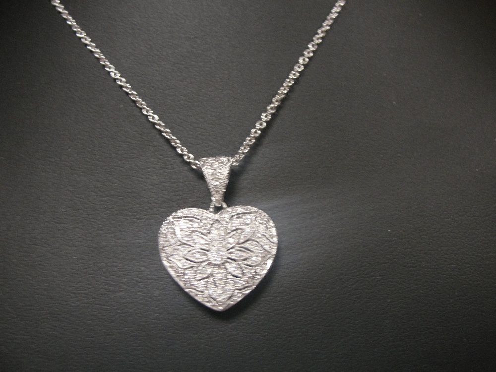 An 18ct filigree diamond set heart and 18ct chain