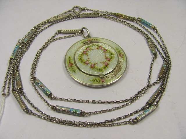 An early 20th century silver enamelled trinket pendant decorated with garlands of flowers on a