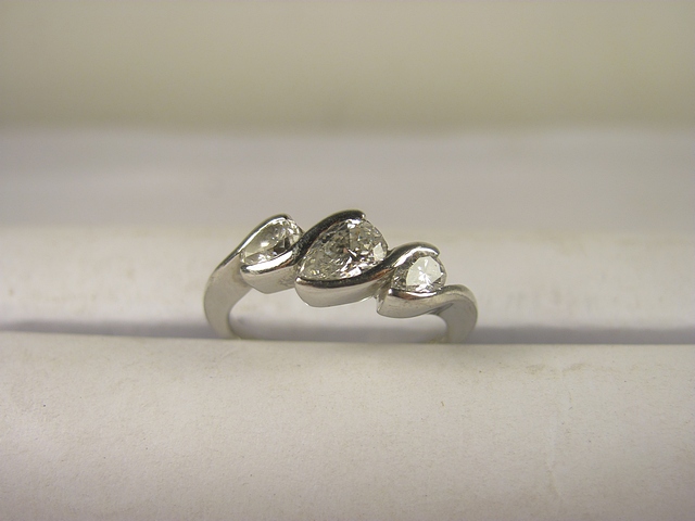 A platinum three stone diamond ring set with pear cut diamonds.