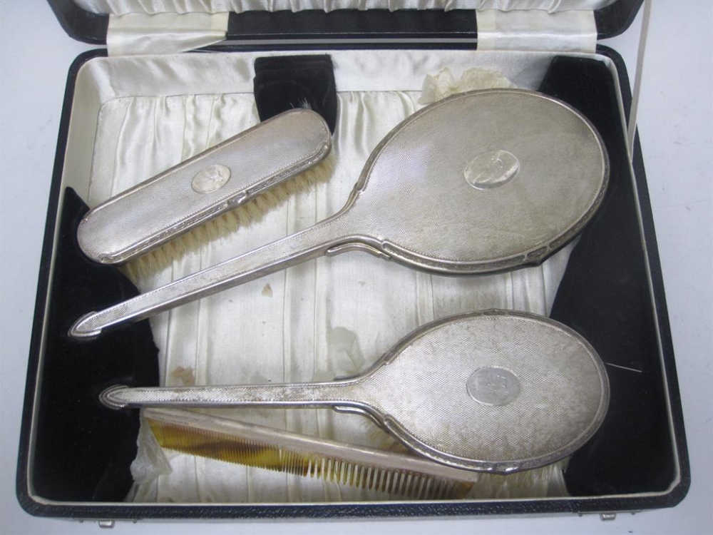 A George VI four piece silver mounted Dressing Table Set with engine turning and monogram,