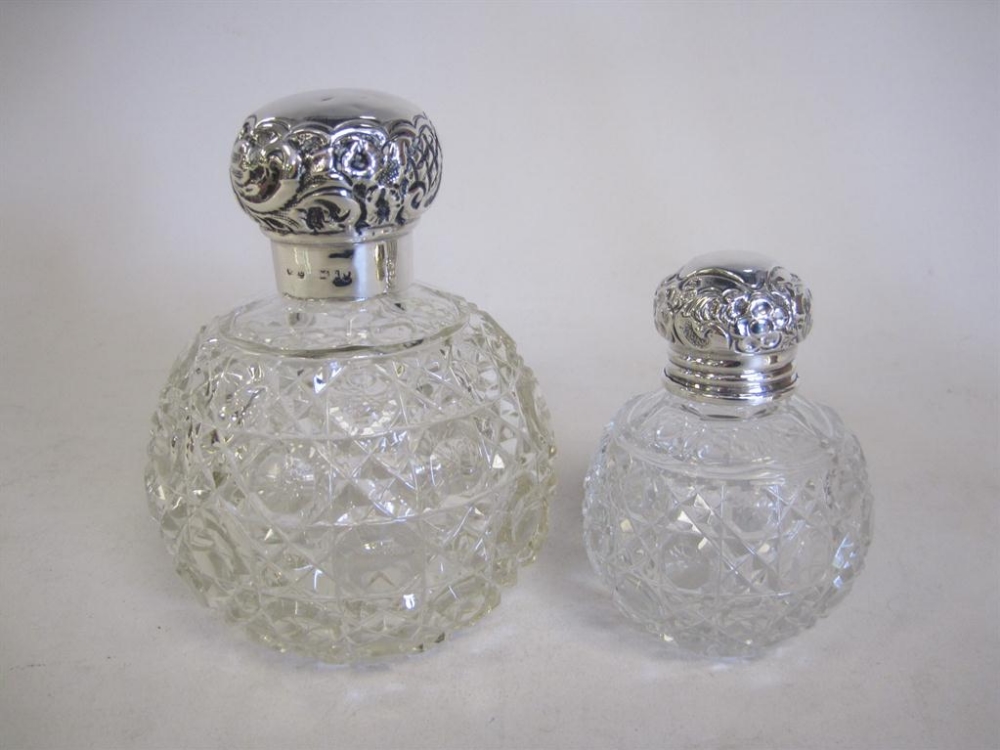 Two silver lidded cut glass globular Scent Bottles with embossed designs, circa 1910
