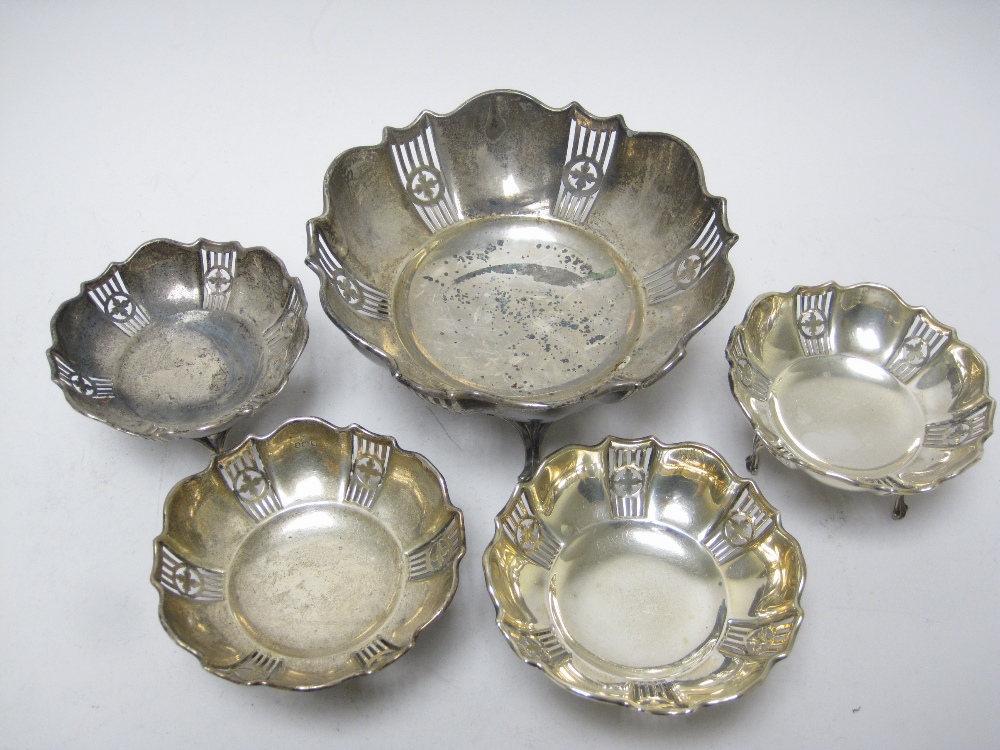 A George V pierced circular Dish on three scroll feet, Birmingham 1919, and four matching smaller