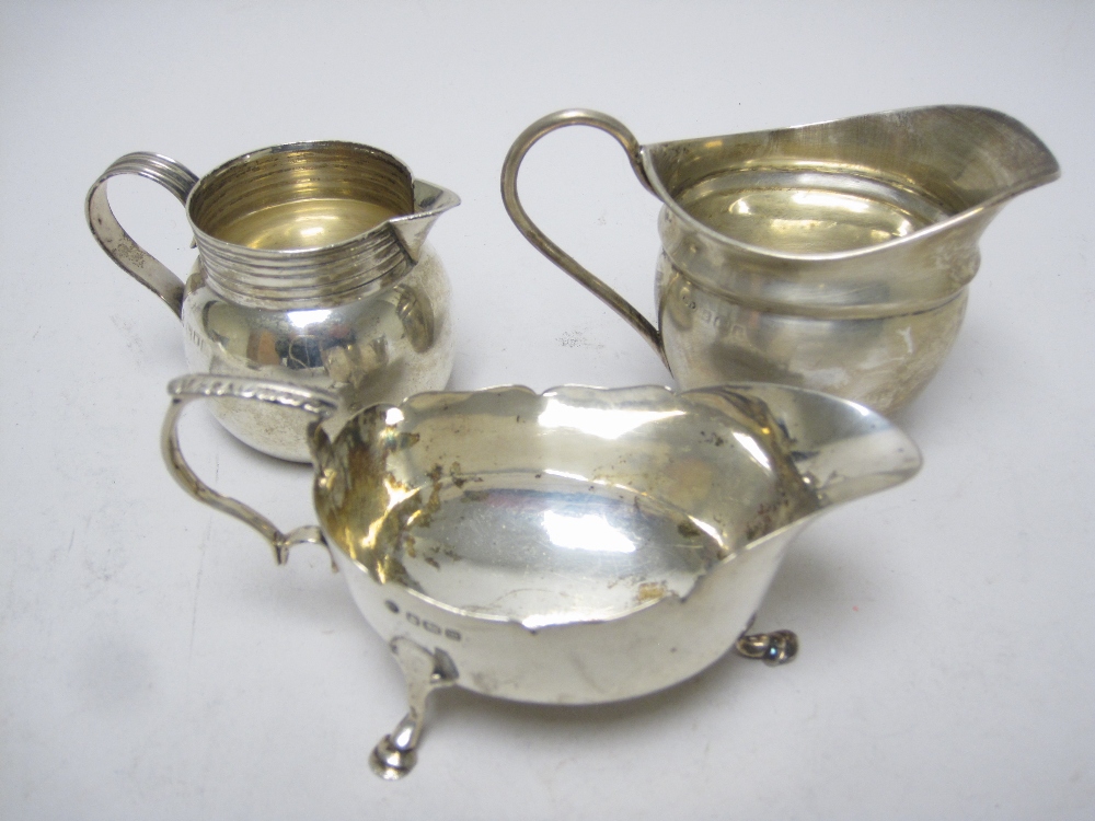 An Edward VII Cream Jug with reeded rim and handle, London 1903, another, Birmingham 1905, and a