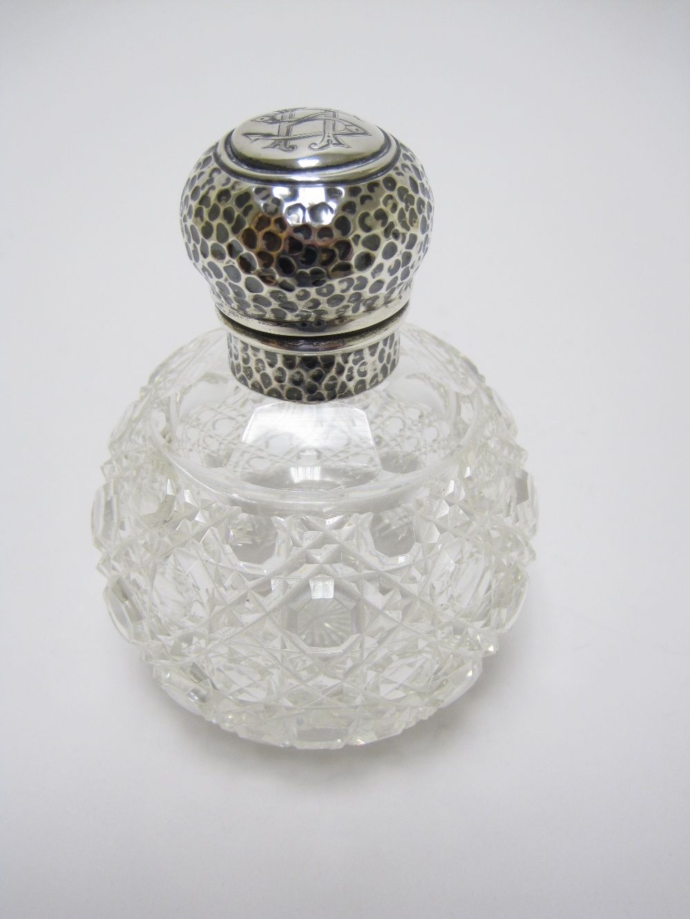 An Edward VII silver lidded cut glass globular Scent Bottle with hammered design, Birmingham 1903