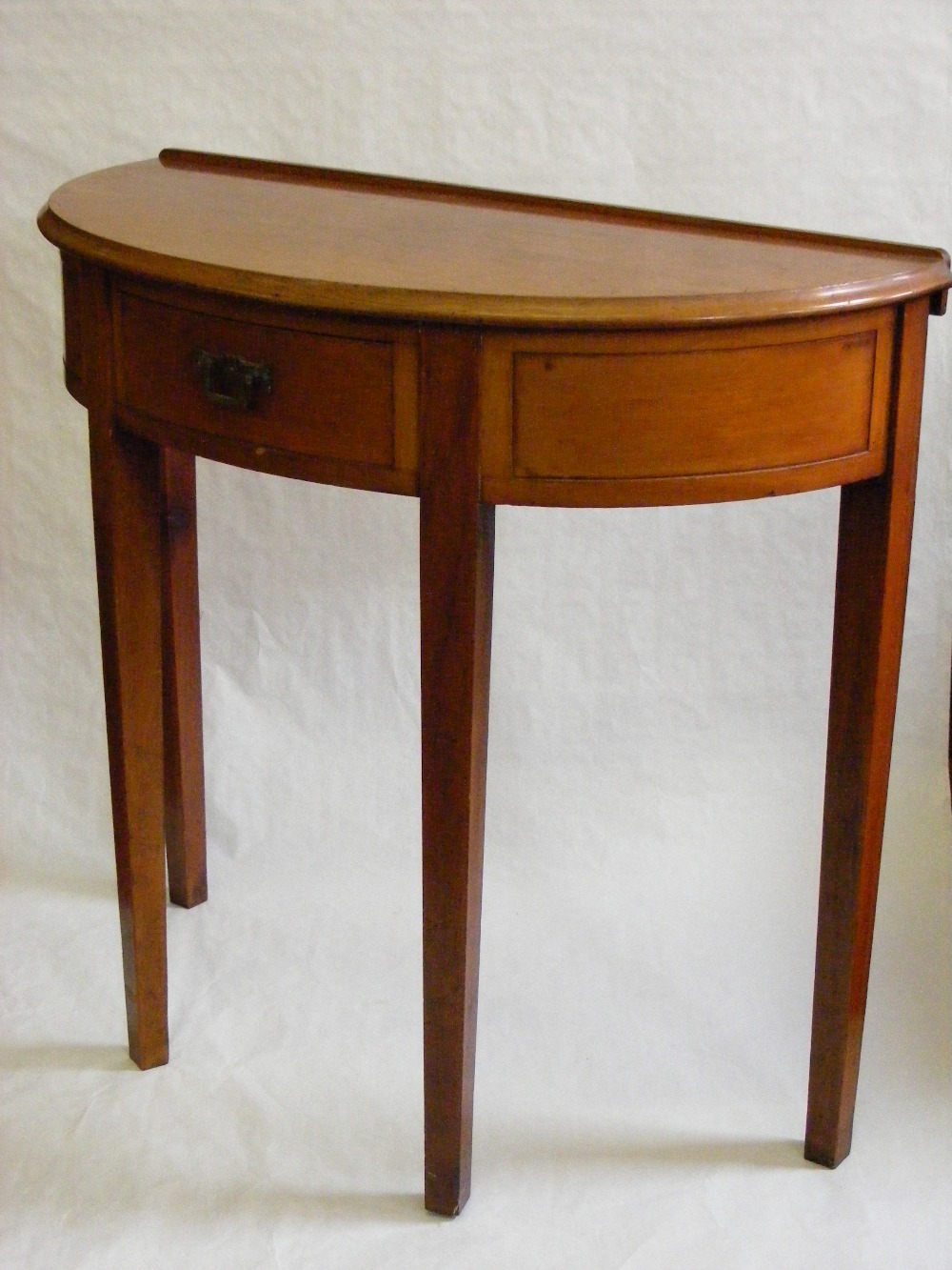 An antique mahogany demi lune hall table on square tapered supports.