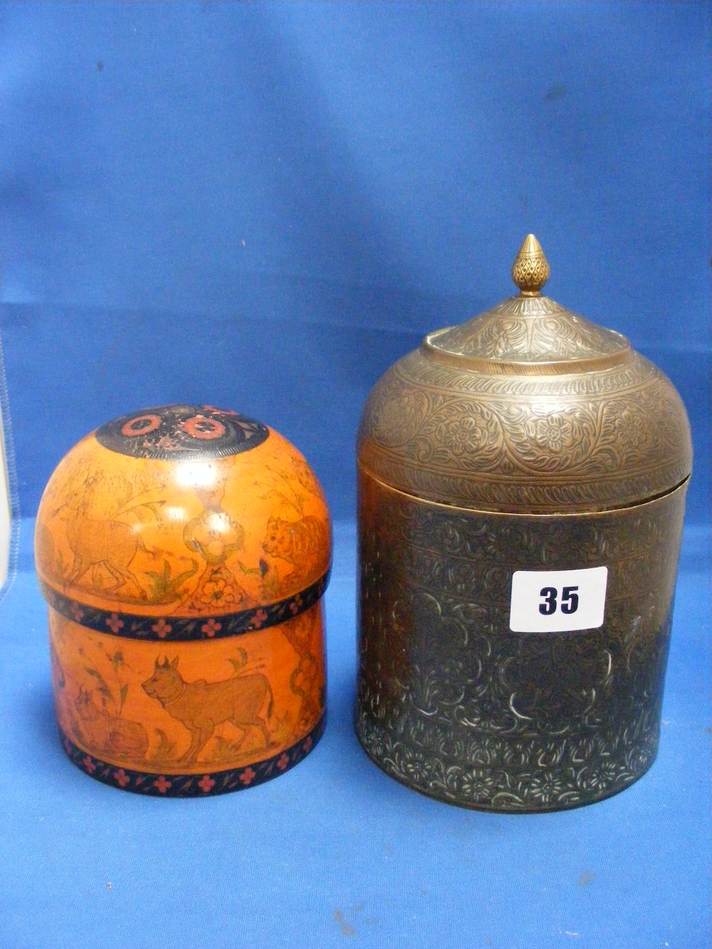 A circular wooden box with dome top decorated with hunting scenes, plus a brass box decorated in