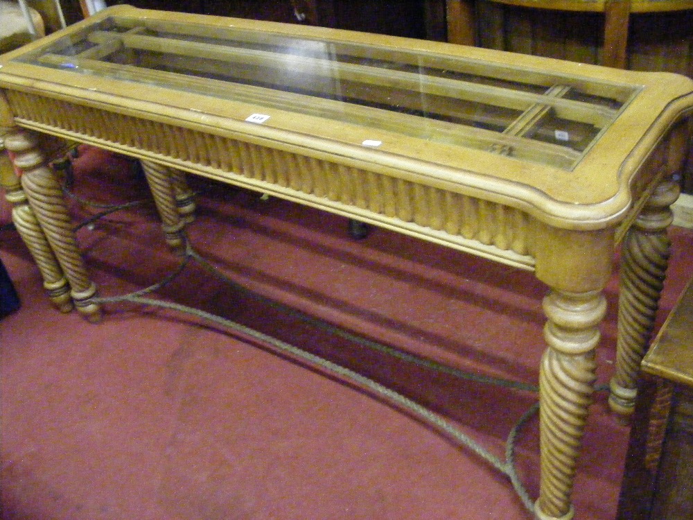 A vintage mahogany glass topped table with decorative frieze, shaped metal stretcher and bobbin
