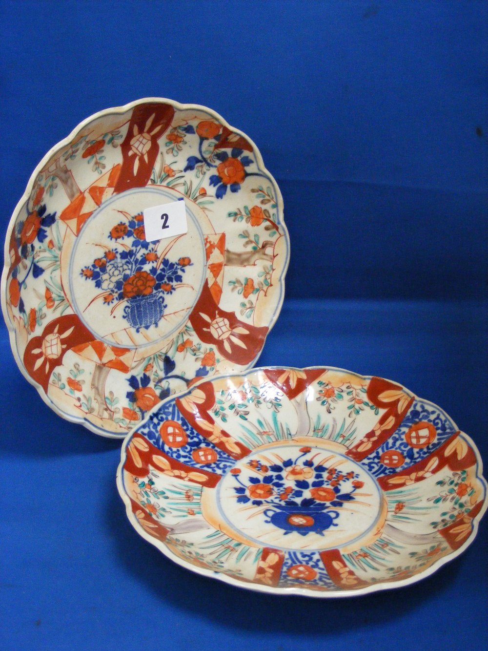 Two Imari dishes of scalloped form, both having a central cartouche of flowers, dia. 22cms.