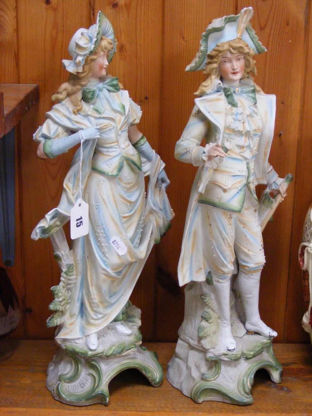 A pair of large Victorian Bisque porcelain figures depicting a gentleman and a lady in Georgian