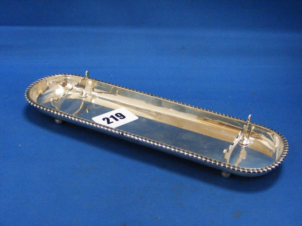 An Edwardian English silver pen tray of oval shape with a ribbed border and shaped pen supports on