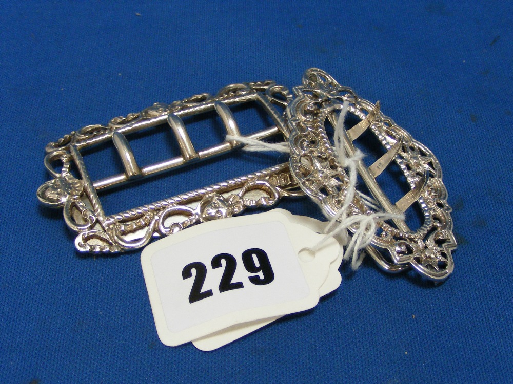 A pair of antique silver buckles the larger example with scroll and flower head detail and the other