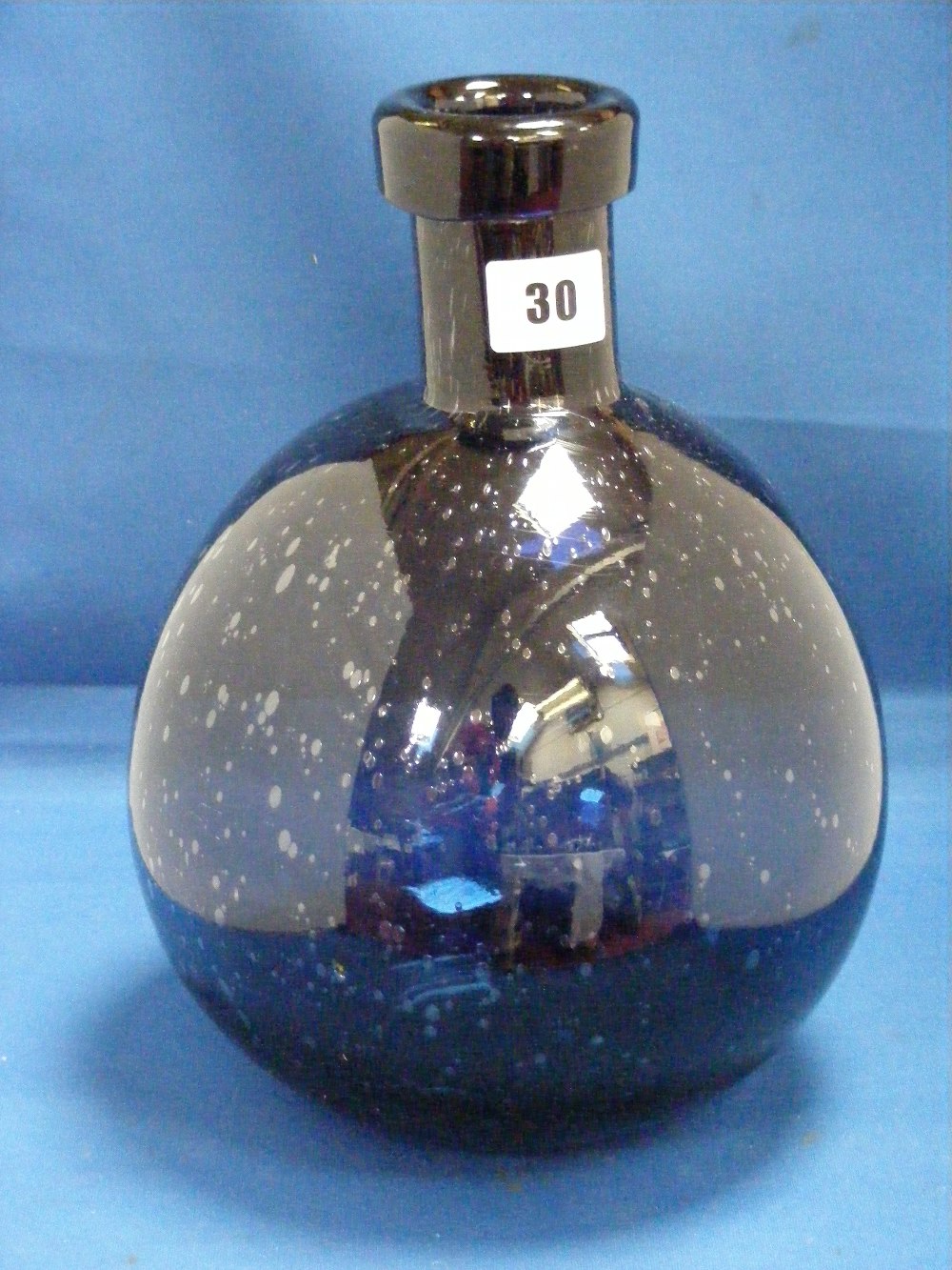 An antique blue glass bottle of circular form and with bubble decoration.
