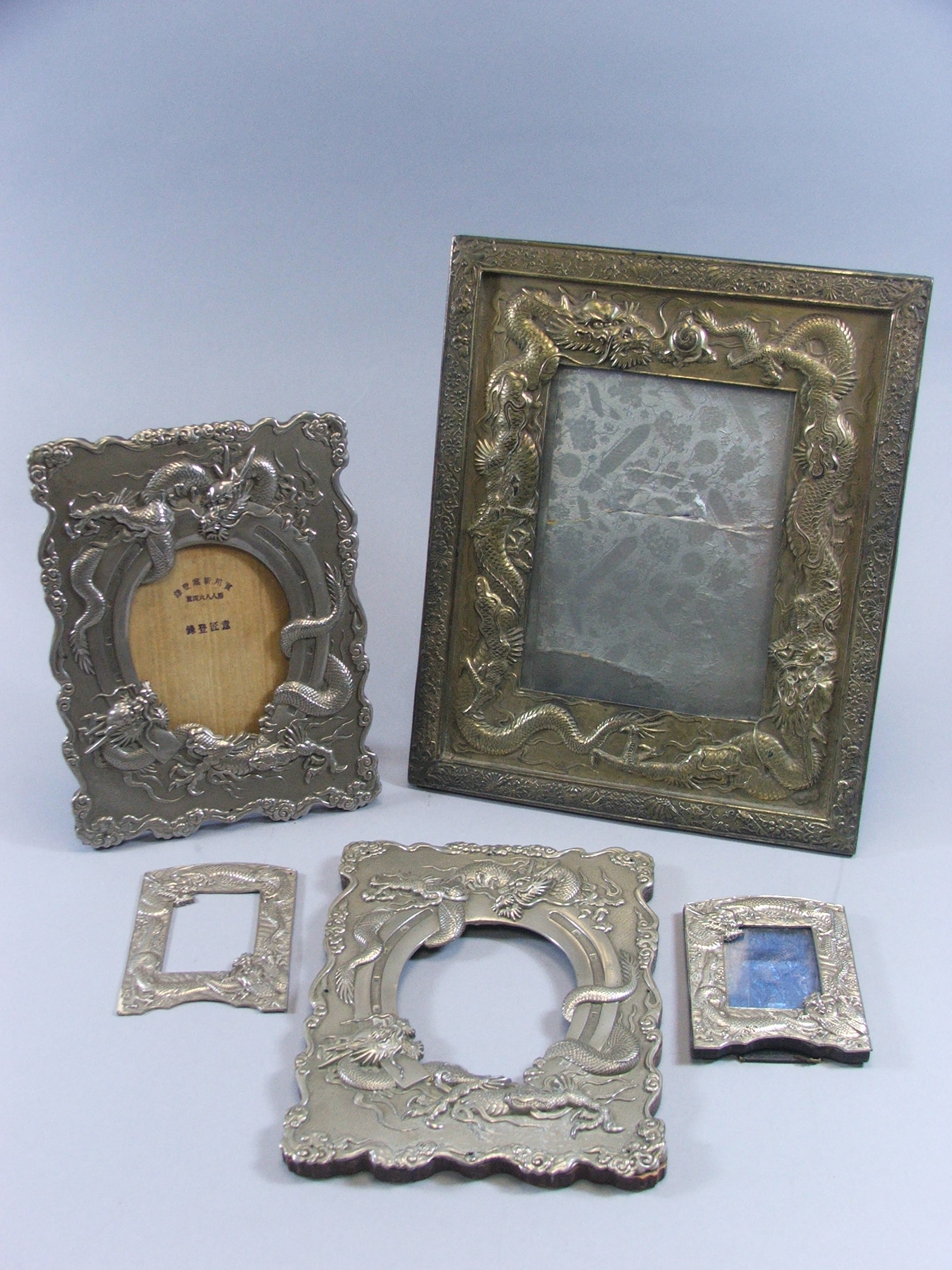 A Collection of Chinese White Metal and Brass Photo Frames all Decorated with Dragons in Relief.