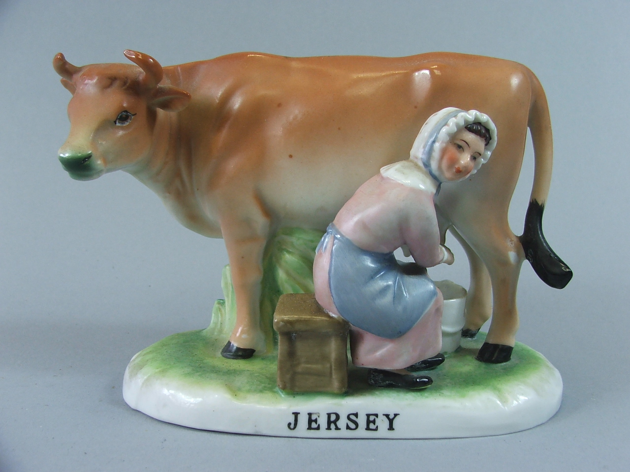A Continental Souvenir Figure Group, Cow and Milkmaid, Jersey, 11 cm High.