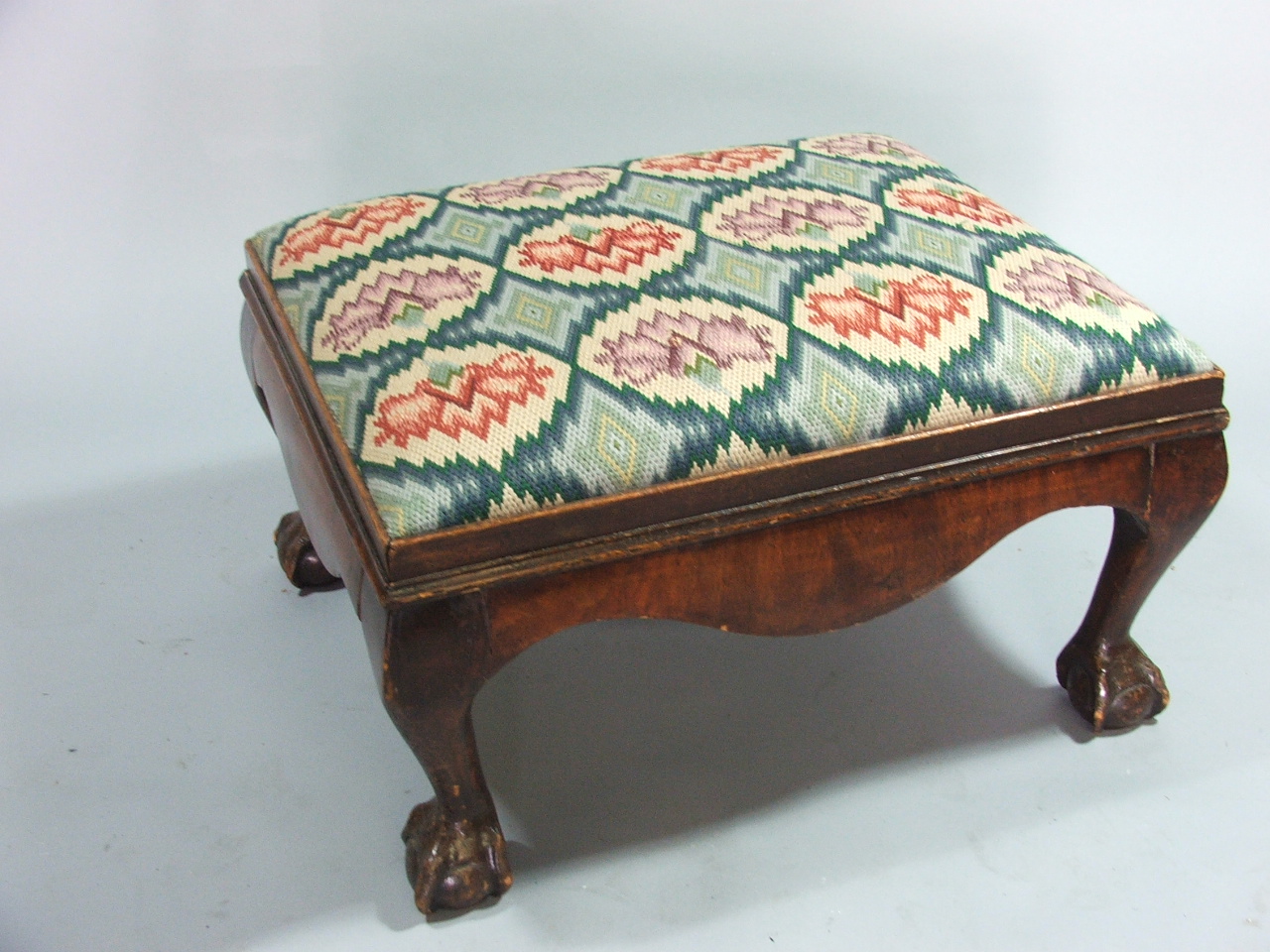 A Georgian Mahogany Tapestry Topped Cushion Shaped Stool on Claw and Ball Feet.