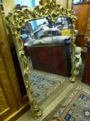 An antique gilt wood mantle mirror having foliate design to the top and sides, approx. 140 cms. high