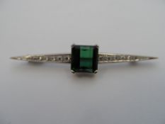 An art deco platinum and diamond pin brooch set with a large centred green tourmaline of approx. 3.2