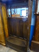 An Edwardian oak mirror backed hall stand / seat having shaped cornice to top, panelled back with