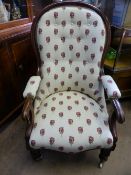 A Victorian mahogany grandmother`s armchair having floral embroidered upholstery