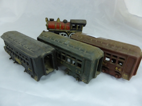 A vintage cast iron train set comprising an engine, tender and three carriages.