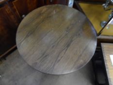 A circular wooden topped pub table on a black cast iron three legged base with a small under