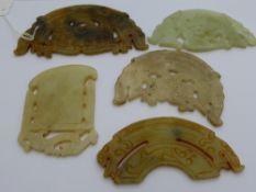 Five jade amulets being of different sizes and various colours with varying designs.