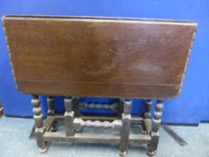 An Edwardian oak drop leaf table having carved decoration to the edge with turned part bobbin legs