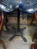 A cast iron bar stool, the seat being from a vintage tractor on a centre column with four splayed