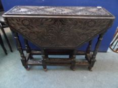 An Edwardian octagonal drop leaf oak table having ornately carved decoration, the table being on