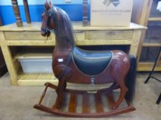 A reproduction wooden rocking horse having studded leather saddle and leather reins, approx. 100